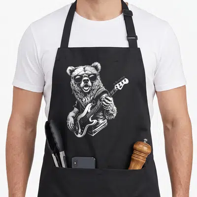 Tablier de cuisine noir avec illustration blanche d'un ours portant des lunettes de soleil et tenant une guitare basse électrique.