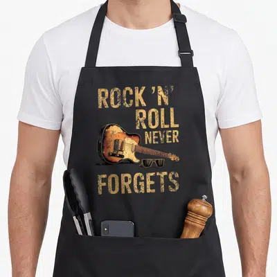 Tablier de cuisine noir avec illustration vintage d'une guitare électrique orange et texte Rock 'n' Roll Never Forgets en jaune.