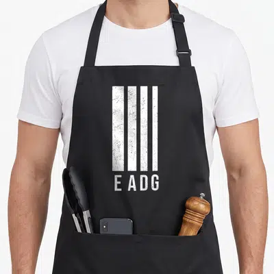 Tablier de cuisine noir avec quatre bandes verticales blanches et le texte EADG en bas.
