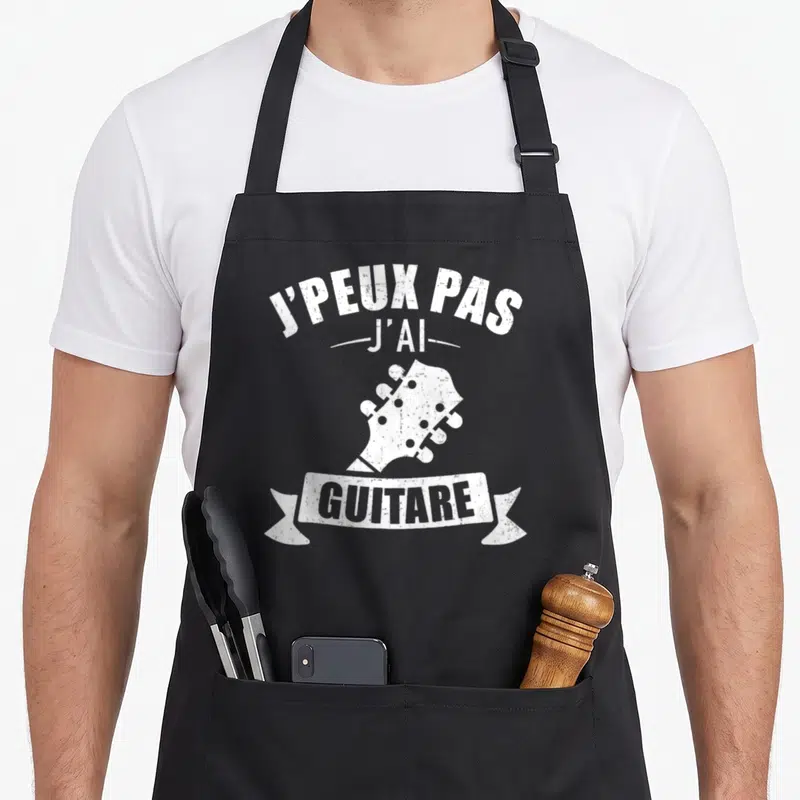 Tablier de cuisine noir avec l'inscription J'peux pas j'ai guitare et une illustration de tête de guitare blanche vintage.