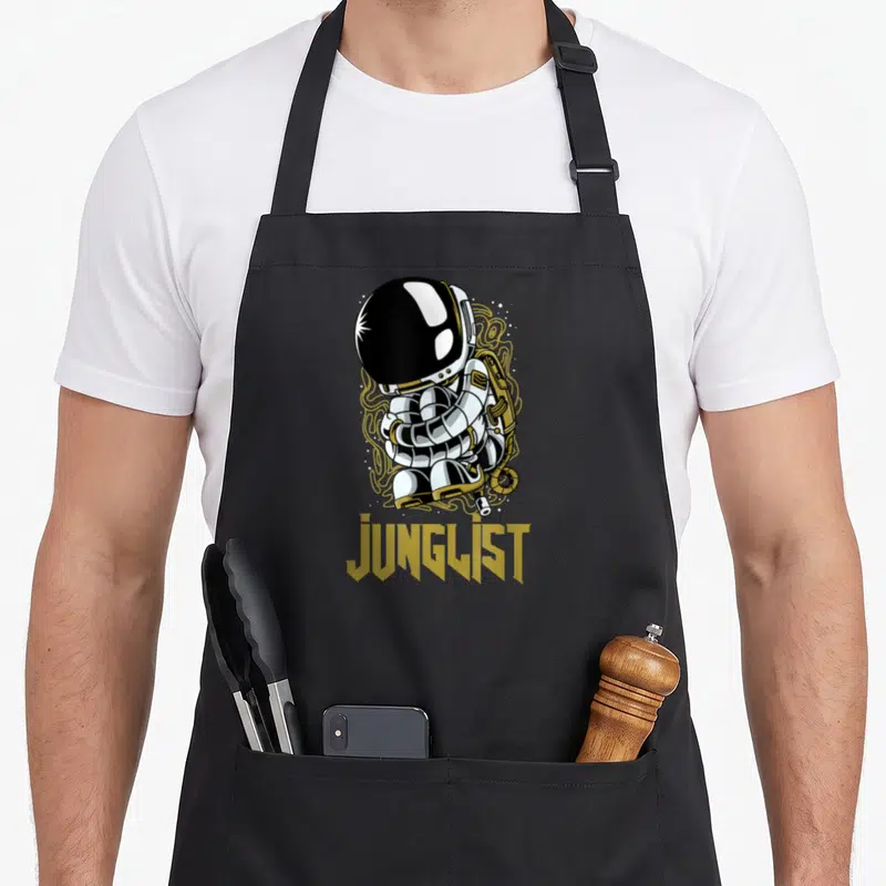 Tablier de cuisine noir avec illustration d'un astronaute jouant d'une basse et du mot Junglist en lettres dorées.