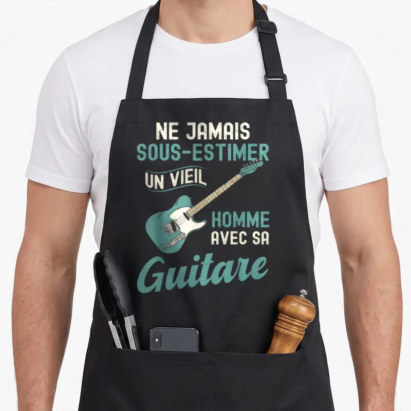 Tablier de cuisine noir avec illustration vintage d'une guitare électrique turquoise et texte humoristique sur fond uni.