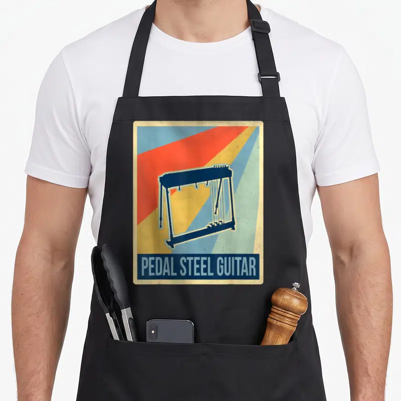 Tablier de cuisine noir avec illustration de pedal steel guitar et texte en anglais sur fond rayé coloré.