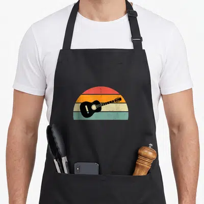 Tablier de cuisine noir avec illustration d'une guitare acoustique noire sur un fond arc-en-ciel retro aux teintes orange et turquoise.