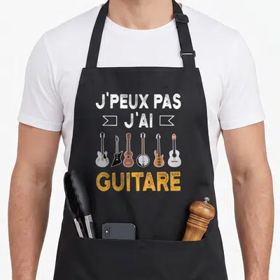 Tablier de cuisine noir avec J'peux pas j'ai guitare et six illustrations d'instruments colorés.