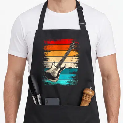 Tablier de cuisine noir avec illustration vintage d'une guitare électrique sur fond de bandes horizontales colorées et délavées.