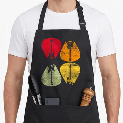 Tablier de cuisine noir avec quatre illustrations de guitares électriques dans des plectres de couleurs vives sur fond uni.
