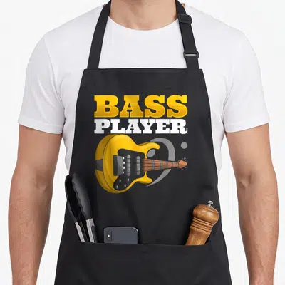 Tablier de cuisine noir avec une basse électrique jaune et l'inscription Bass Player en lettres orange et blanches.