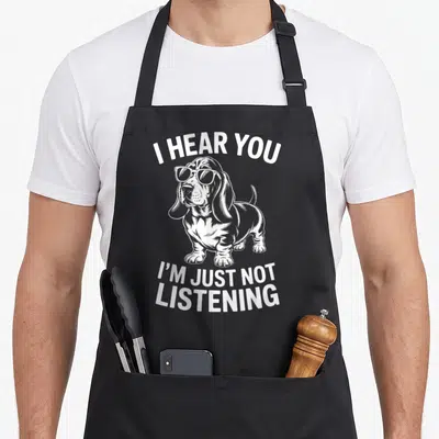 Tablier de cuisine noir avec illustration blanche d'un Basset Hound portant des lunettes de soleil et un texte humoristique en anglais.