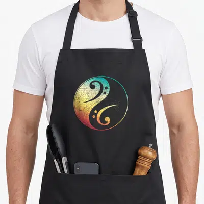 Tablier de cuisine noir avec un motif circule Yin Yang intégrant une clé de sol aux couleurs dégradées et effet vieilli.