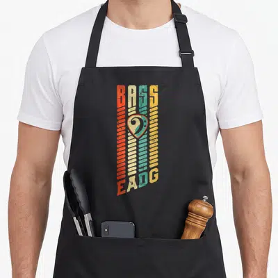 Tablier de cuisine noir avec design vertical multicolore représentant des cordes de basse et une clé de fa stylisée au centre.