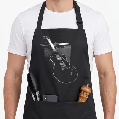 Tablier de cuisine noir avec une guitare électrique et un ampli de blues dessinés en lignes blanches.