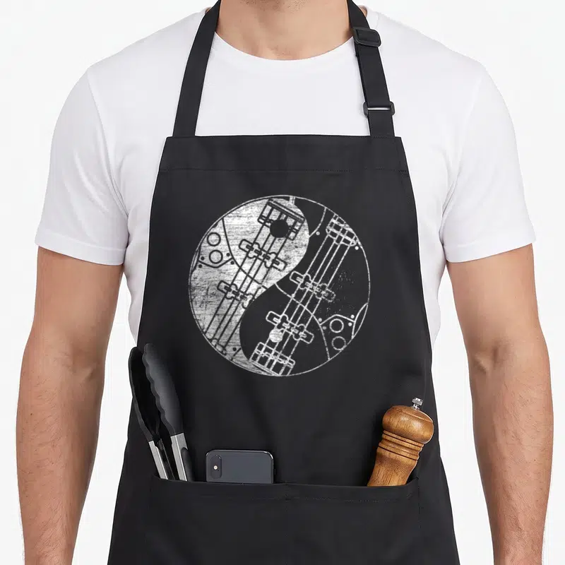 Tablier de cuisine noir avec motif circulaire blanc représentant un yin-yang composé de basses guitars détaillées.