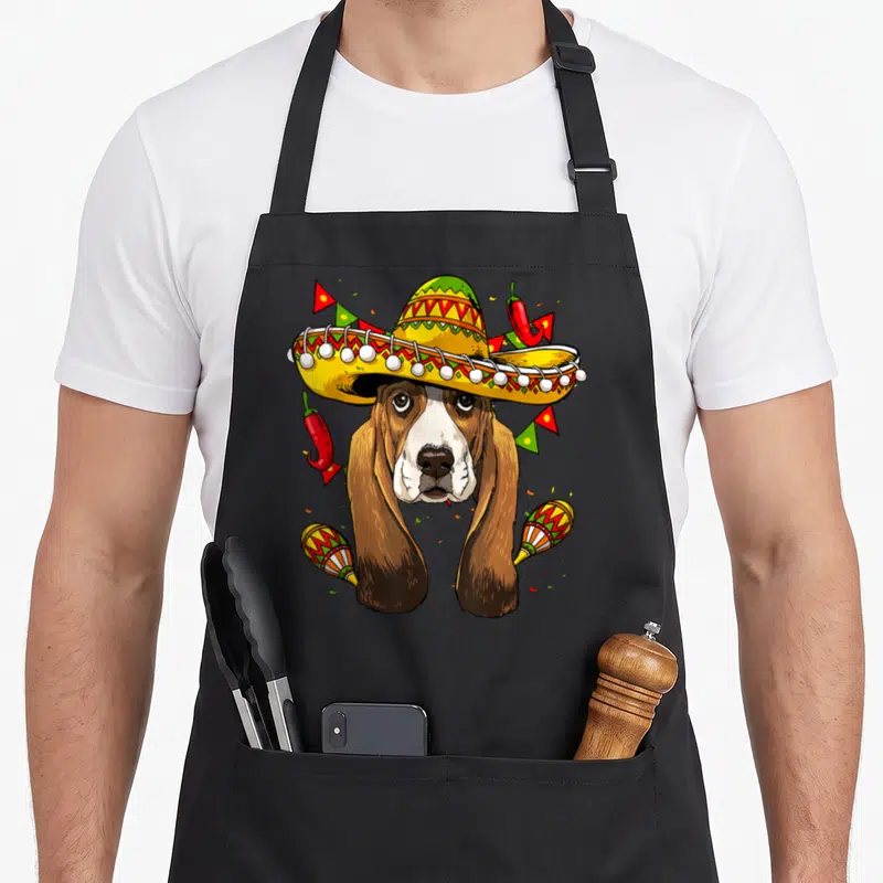 Tablier de cuisine noir avec un basset hound portant un sombrero jaune et des maracas colorées.