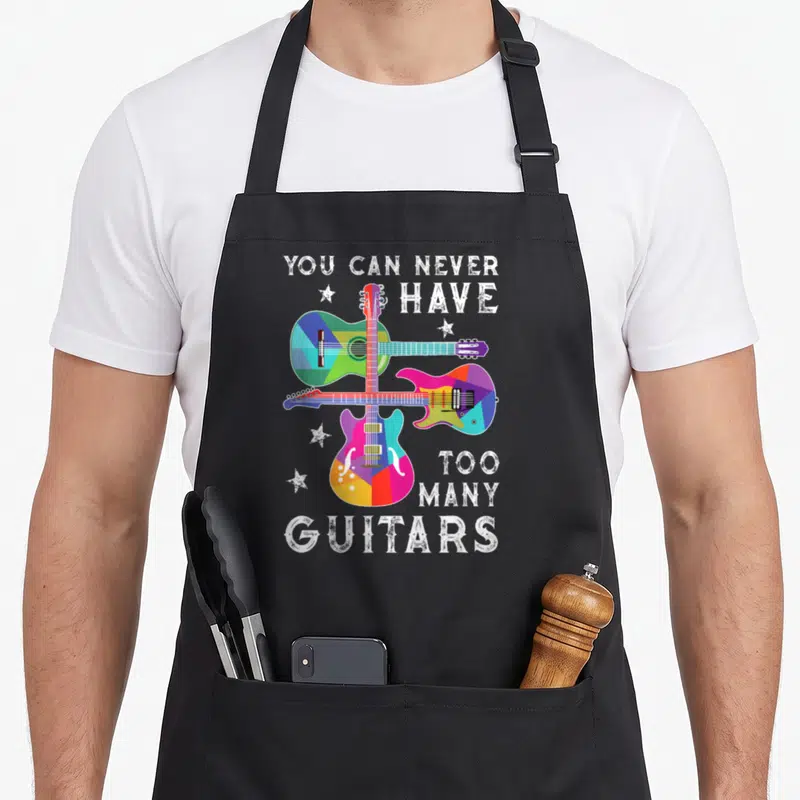 Tablier de cuisine noir avec trois guitares géométriques multicolores et texte blanc You Can Never Have Too Many Guitars.