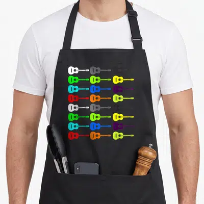 Tablier de cuisine noir avec un motif repeating d'ukuléles stylisées blanches, grises, noires, vertes, jaunes, bleues, violettes et oranges.