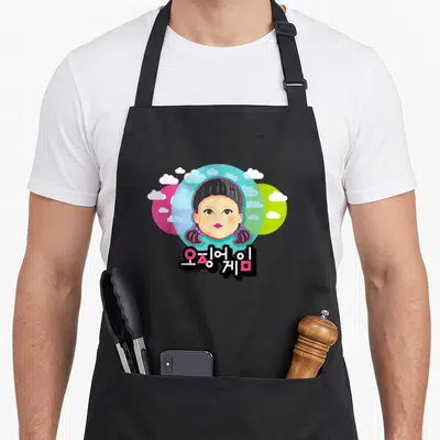 Tablier de cuisine noir avec une poupée aux tresses roses et des nuages sur des cercles rose bleu et vert clair.