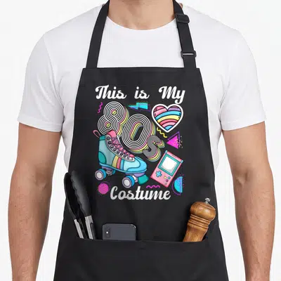 Tablier de cuisine noir avec illustration patins à roulettes, console portable rose et texte This is My 80's Costume en style néon.