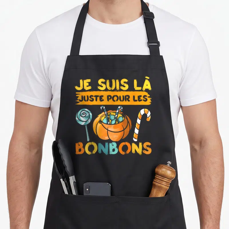 Tablier de cuisine noir avec inscription Je suis là juste pour les bonbons et illustrations de sucreries colorées.