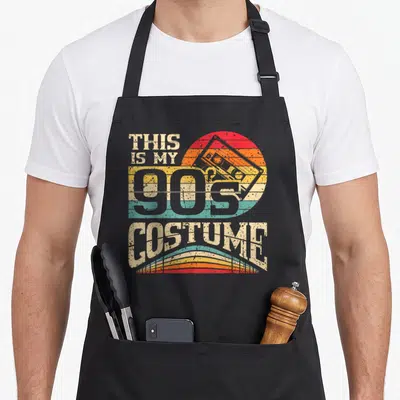 Tablier de cuisine noir avec motif This Is My 90s Costume et illustration de cassette vintage colorée.