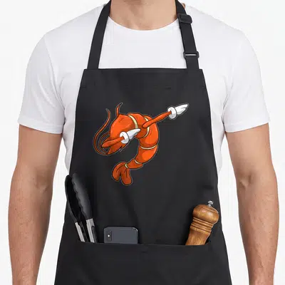 Tablier de cuisine noir avec une illustration d'une crevette orange effectuant un mouvement de danse dab.