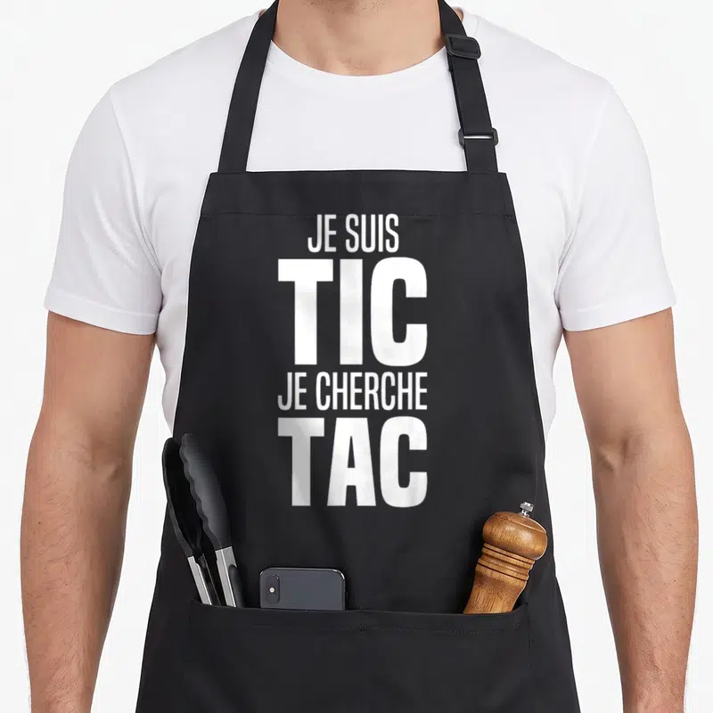 Tablier de cuisine noir avec inscription blanche « Je suis TIC je cherche TAC » en typographie verticale bold.