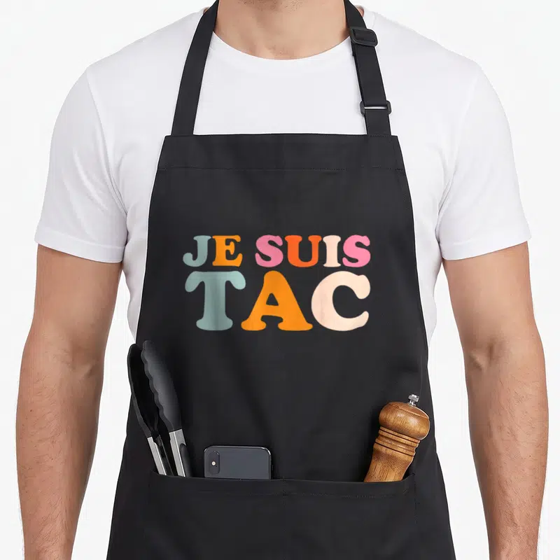 Tablier de cuisine noir avec l'inscription Je suis TAC en lettres pastel multicolores et épaisses.