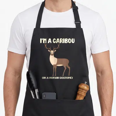 Tablier de cuisine noir avec illustration d'un caribou et le texte I'M A CARIBOU IN A HUMAN COSTUME en lettres claires.