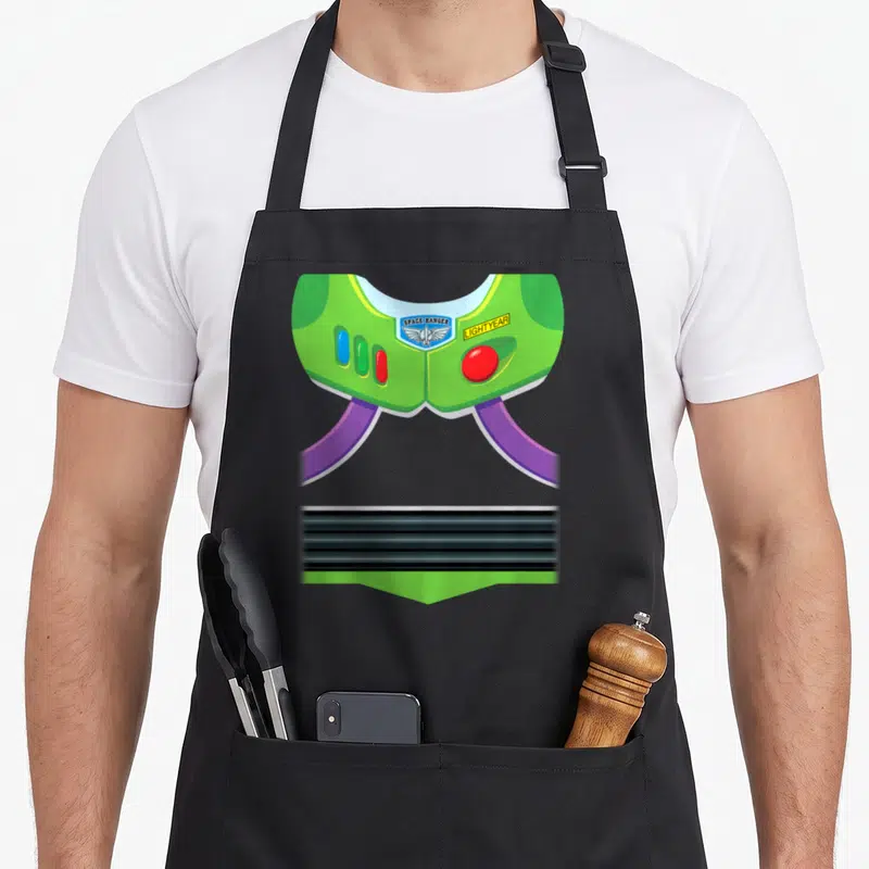 Tablier de cuisine noir avec illustration du gilet vert de Buzz Lightyear Space Ranger, badges et bandes noires.