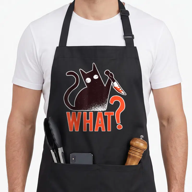 Tablier de cuisine noir avec un chat noir tenant un couteau ensanglanté et le texte WHAT? en orange.