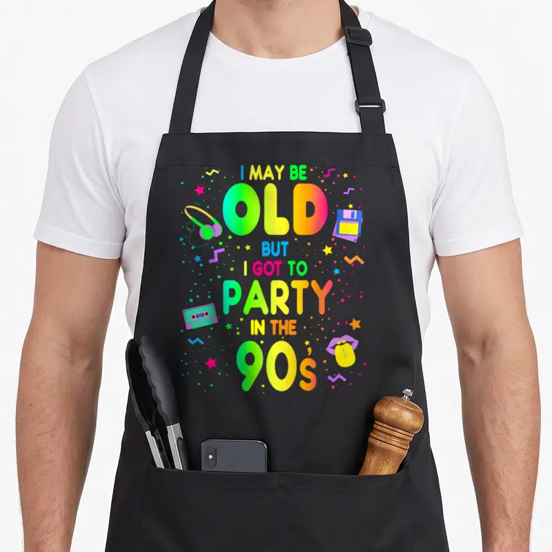 Tablier de cuisine noir avec texte I may be old but i got to party in the 90s et illustrations rétro années 90 colorées.