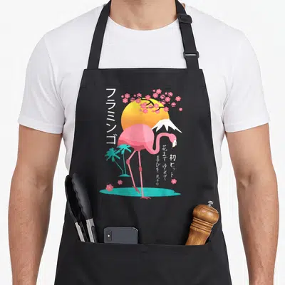 Tablier de cuisine noir avec un flamant rose rose devant le mont Fuji, un soleil orange et des branches de sakura roses.