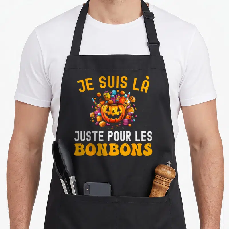 Tablier de cuisine noir avec un pumpkin rempli de bonbons et le texte Je suis là juste pour les bonbons.
