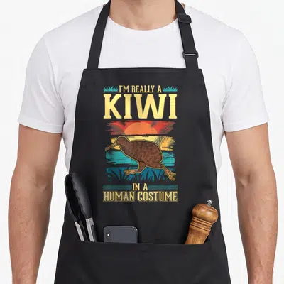 Tablier de cuisine noir avec illustration vintage d'un oiseau kiwi et texte humoristique sur fond de soleil tropical.