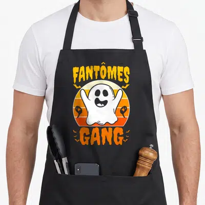 Tablier de cuisine noir avec un fantôme blanc souriant, le texte Fantômes Gang et des motifs de chauves-souris orange sur fond rétro.