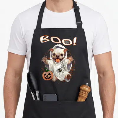 Tablier de cuisine noir avec un bouledogue français déguisé en fantôme tenant une citrouille et le texte Boo au-dessus.