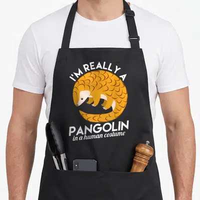 Tablier de cuisine noir avec illustration d'un pangolin orange et texte blanc en anglais.