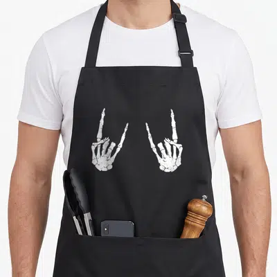 Tablier de cuisine noir avec deux mains squelettiques blanches faisant le signe du rock.