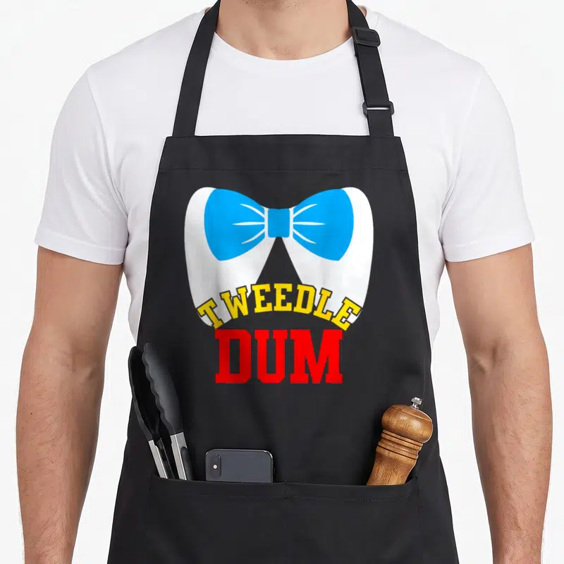 Tablier de cuisine noir avec grand nœud papillon bleu et texte Tweedle Dum en jaune et rouge.