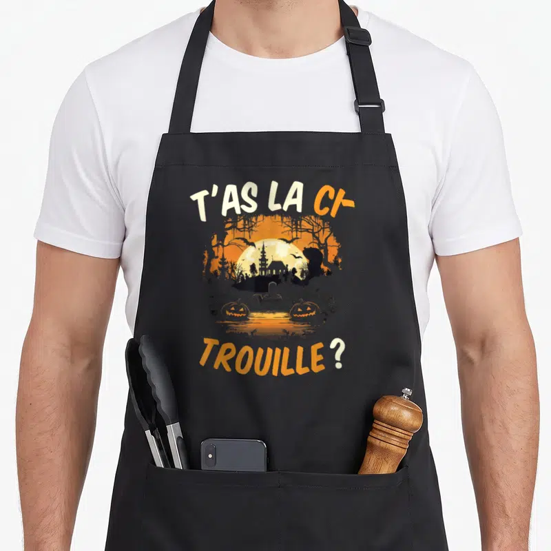 Tablier de cuisine noir avec illustration d'un paysage halloween montrant un château et des citrouilles sous une pleine lune.