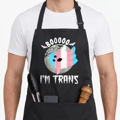 Tablier de cuisine noir avec un fantôme aux couleurs du drapeau transgenre devant une lune et le texte Booo I'm Trans.
