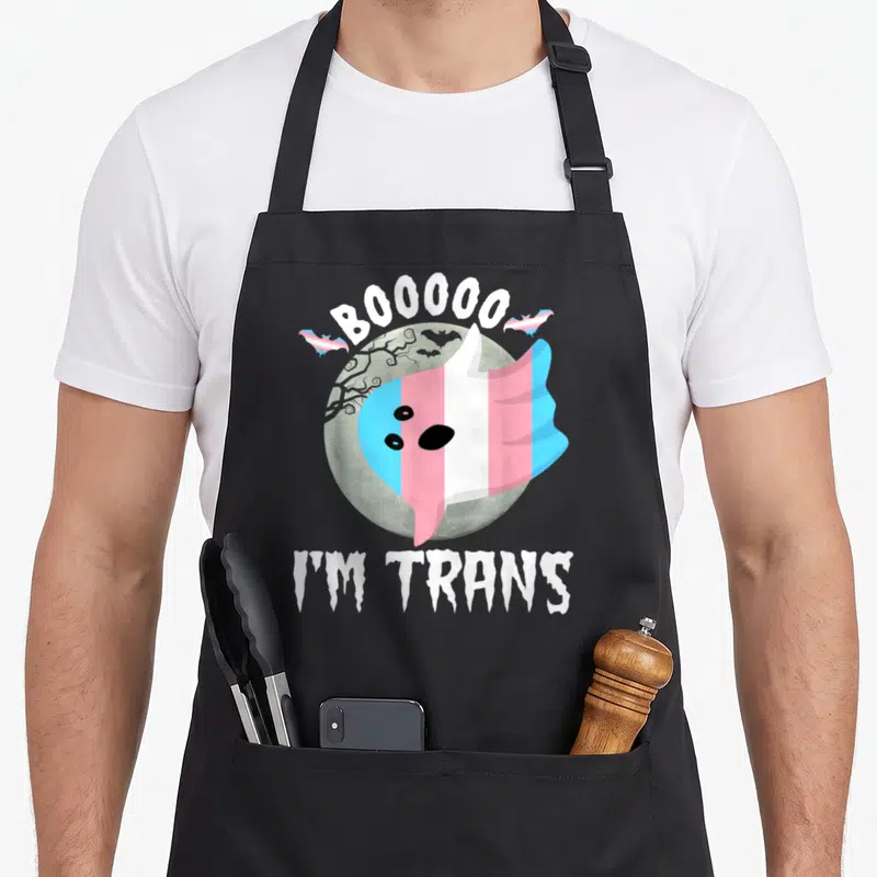 Tablier de cuisine noir avec un fantôme aux couleurs du drapeau transgenre devant une lune et le texte Booo I'm Trans.
