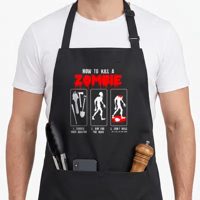 Tablier de cuisine noir avec motif How to Kill a Zombie en rouge et blanc illustrant des armes et des silhouettes de zombies.