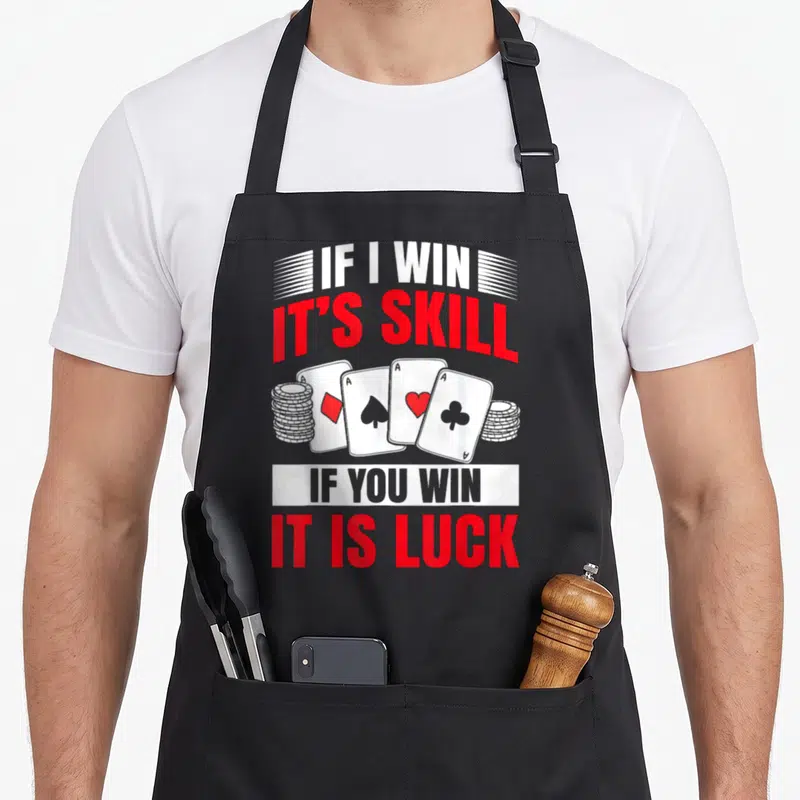 Tablier de cuisine noir avec quatre as, piles de jetons et texte rouge If I Win It's Skill If You Win It Is Luck.