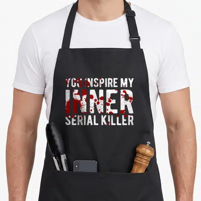Tablier de cuisine noir avec inscription blanche et taches rouges évoquant du sang.