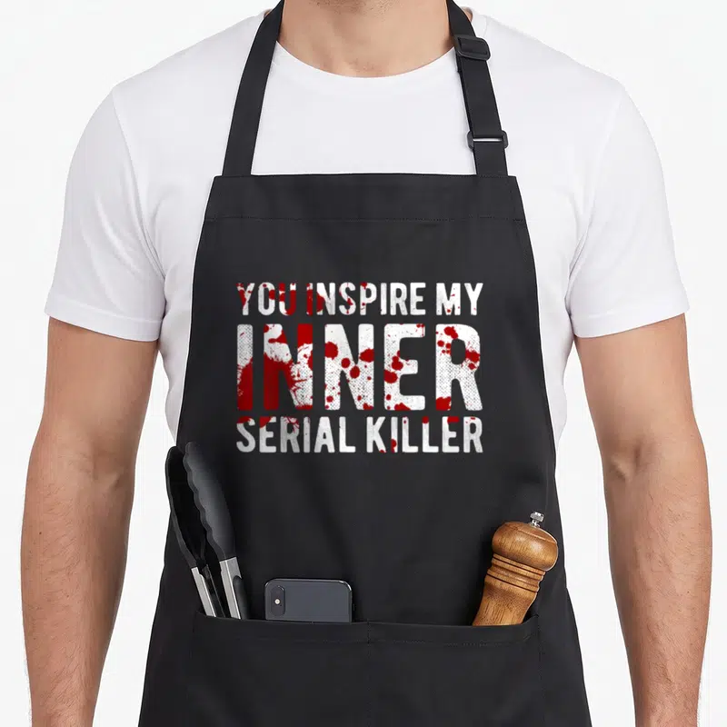 Tablier de cuisine noir avec inscription blanche et taches rouges évoquant du sang.