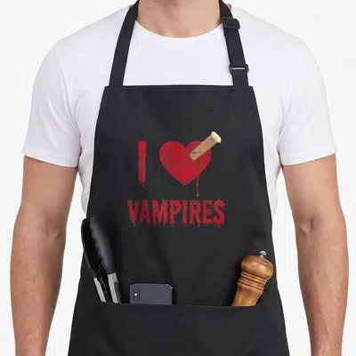 Tablier de cuisine noir avec un cœur rouge percé d'un clou en bois et le texte Vampires en lettres rouges dégoulinantes.