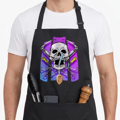 Tablier de cuisine noir avec un crâne médical entouré de seringues jaunes et d'instruments chirurgicaux croisés.