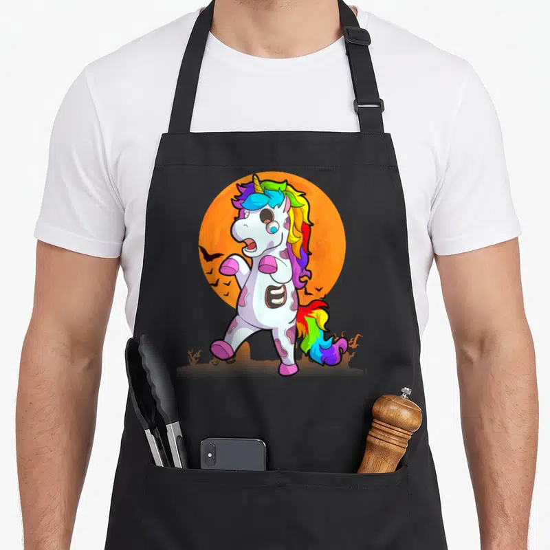 Tablier de cuisine noir avec une licorne zombie aux couleurs vives et un soleil orange en arrière-plan.
