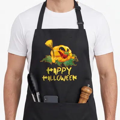 Tablier de cuisine noir avec un pumpkin souriant effrayant et l'inscription Happy Halloween en jaune.